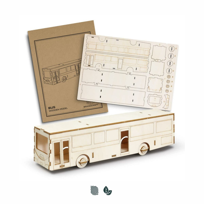 A wooden model bus kit with unassembled parts and instructions. The model is light wood in colour.